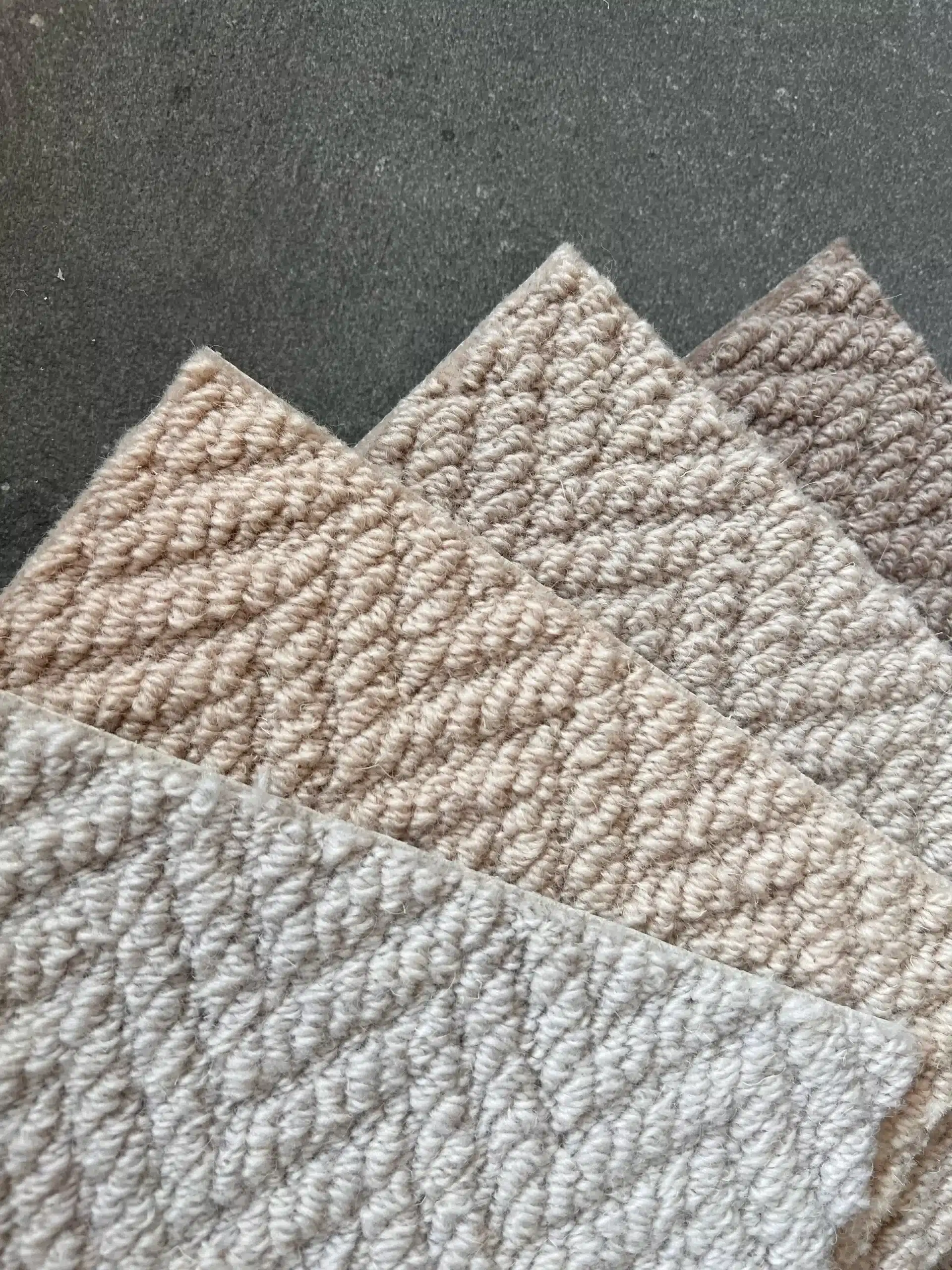 Drie tinten wol naast elkaar leggen Drie wollen tapijtstalen met lussenpool in crème, beige en taupe, waaiervormig over elkaar