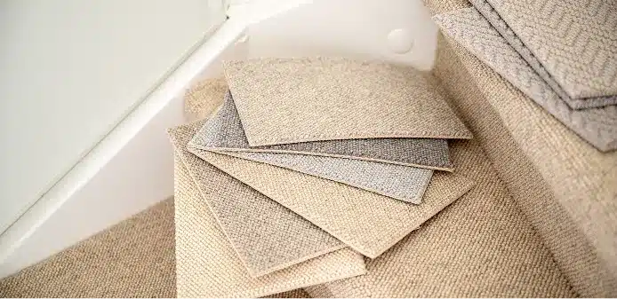 Waaier van wollen tapijtstalen in beige en grijze weefsels op een beklede traptrede