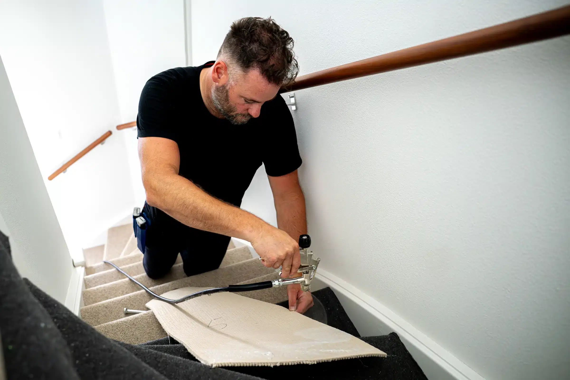 Wollen trap bekleden met de tacker Stoffeerder zet met een pneumatische tacker wollen trapbekleding vast op een traptrede